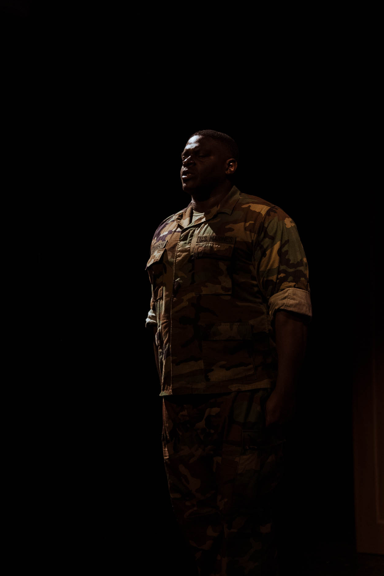 A Marine standing alone in a single spotlight